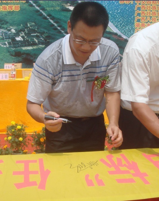 廣西新港灣公司副總經(jīng)理姚方明在“奮戰100天，如期實(shí)現魚(yú)梁工程截流、通航、發(fā)電‘三大目標’”橫幅上簽字